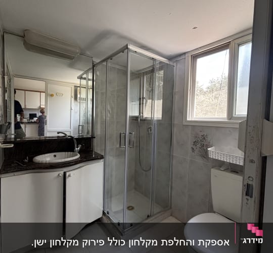 מקלחת עם דלת זכוכית, כיור ושירותים בחדר אמבטיה